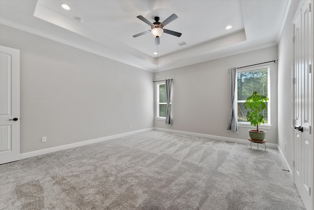 unfurnished room with a raised ceiling, ornamental molding, ceiling fan, and a wealth of natural light