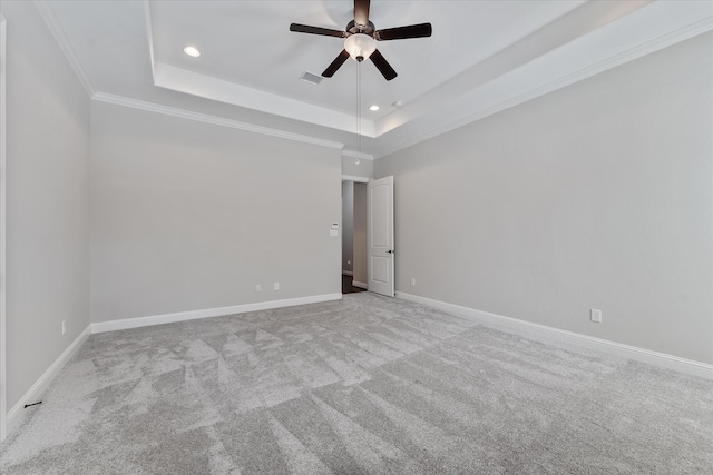 carpeted spare room with ceiling fan, a raised ceiling, and crown molding