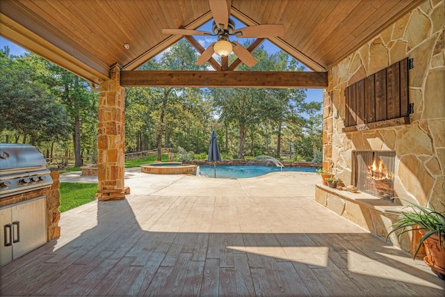 view of patio featuring area for grilling, a grill, ceiling fan, an outdoor stone fireplace, and pool water feature