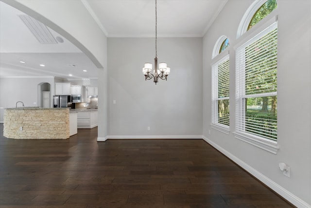 unfurnished dining area featuring crown molding, dark wood-type flooring, and a notable chandelier