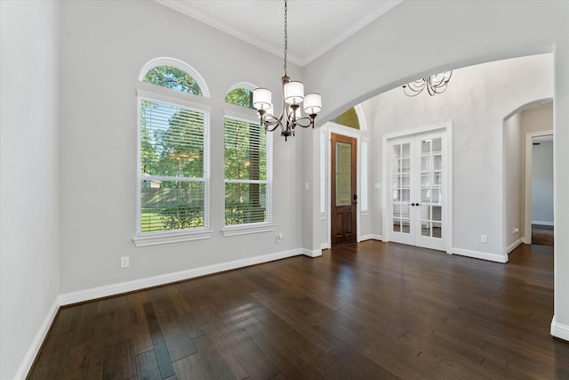 unfurnished room with an inviting chandelier, dark wood-type flooring, and a healthy amount of sunlight