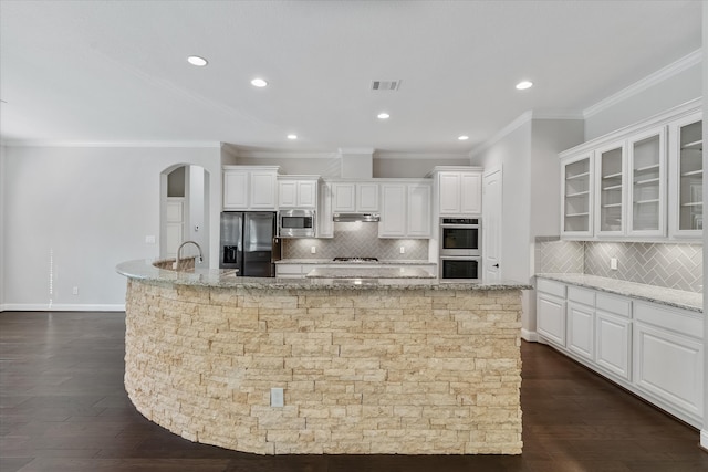 kitchen featuring stainless steel appliances, white cabinets, light stone counters, and dark wood-type flooring