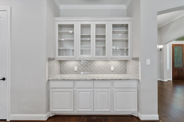 kitchen featuring light stone counters, dark wood-type flooring, tasteful backsplash, white cabinetry, and ornamental molding