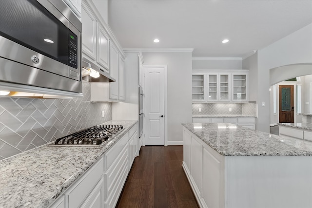 kitchen featuring light stone counters, dark wood-type flooring, white cabinets, stainless steel appliances, and backsplash