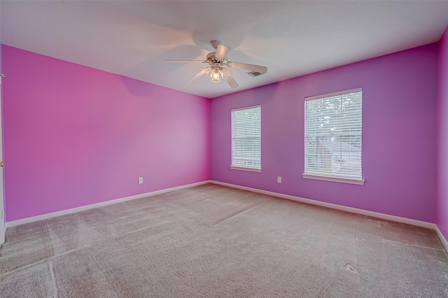 spare room featuring carpet, visible vents, ceiling fan, and baseboards