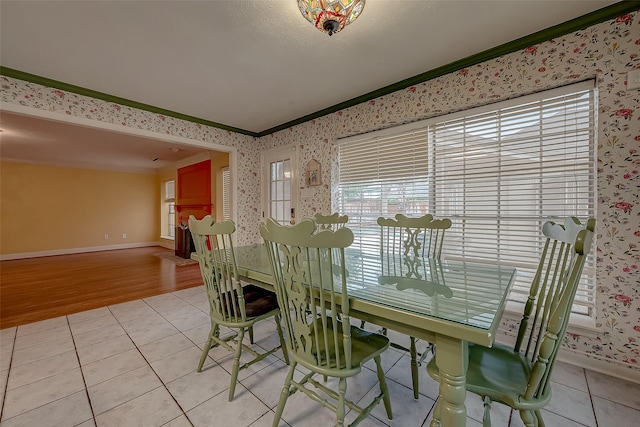 dining room with wallpapered walls, light tile patterned floors, baseboards, and crown molding