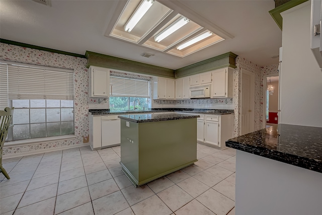 kitchen with light tile patterned flooring, white appliances, white cabinets, a center island, and sink