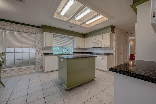 kitchen featuring a center island, white cabinets, a sink, white appliances, and wallpapered walls