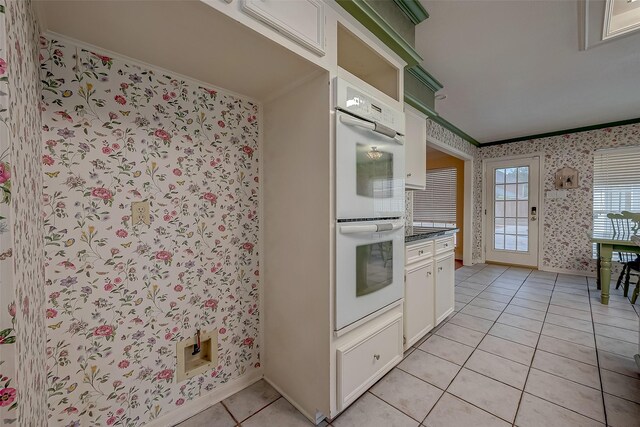 kitchen featuring white cabinets, ornamental molding, light tile patterned floors, and double oven