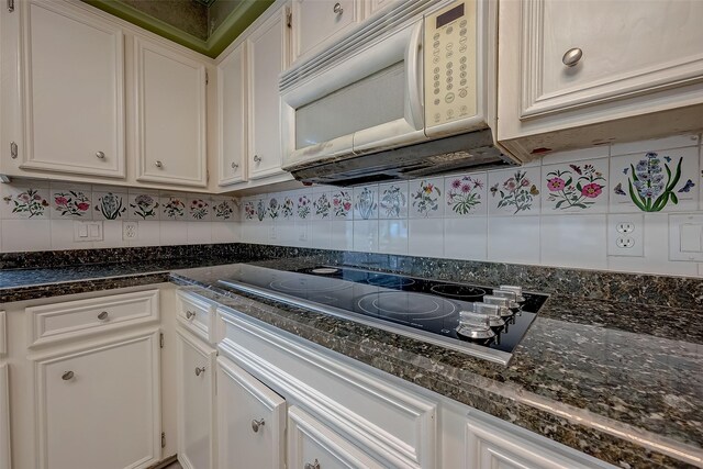 kitchen with dark stone countertops, electric cooktop, white cabinetry, and decorative backsplash