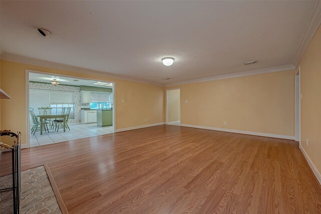 unfurnished living room with crown molding and light hardwood / wood-style flooring