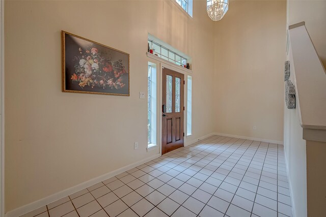 foyer entrance featuring a notable chandelier, light tile patterned floors, and a high ceiling