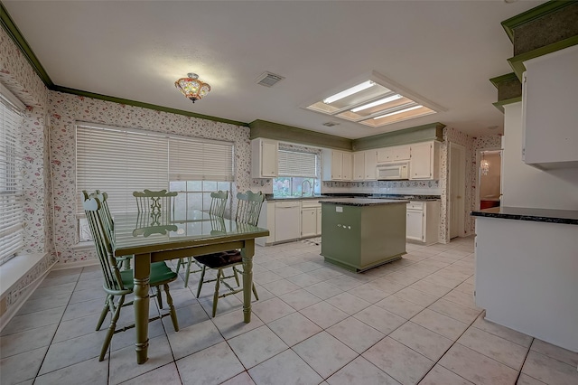 kitchen with wallpapered walls, visible vents, dark countertops, white microwave, and white cabinetry