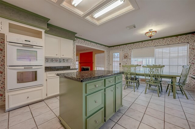 kitchen featuring light tile patterned flooring, a center island, white cabinetry, and white double oven