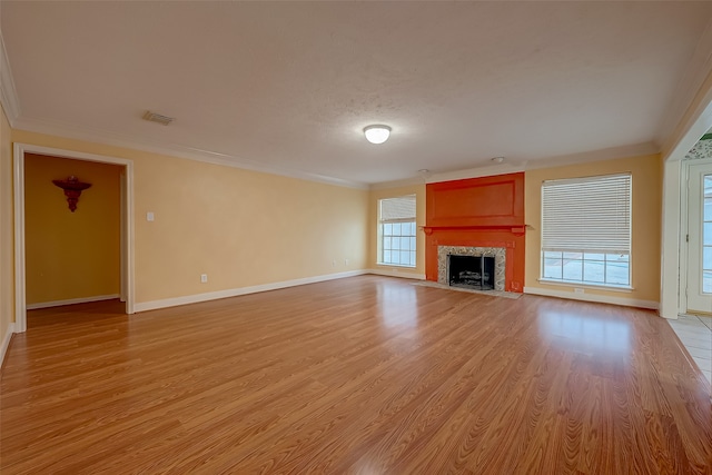 unfurnished living room featuring a fireplace, crown molding, and light wood-type flooring