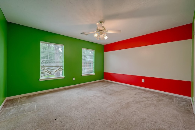 spare room with baseboards, ceiling fan, visible vents, and light colored carpet