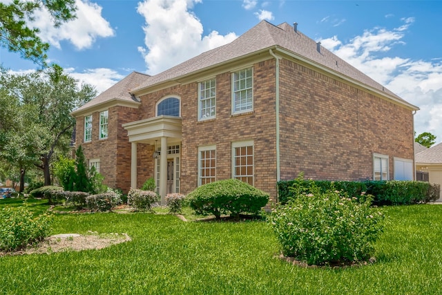 view of front of home featuring a garage, a front yard, and brick siding