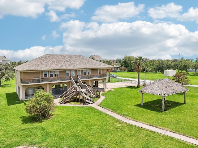 back of property with roof with shingles, a lawn, and stairway