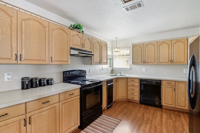 kitchen featuring light brown cabinets, light wood-type flooring, a textured ceiling, beverage cooler, and black appliances