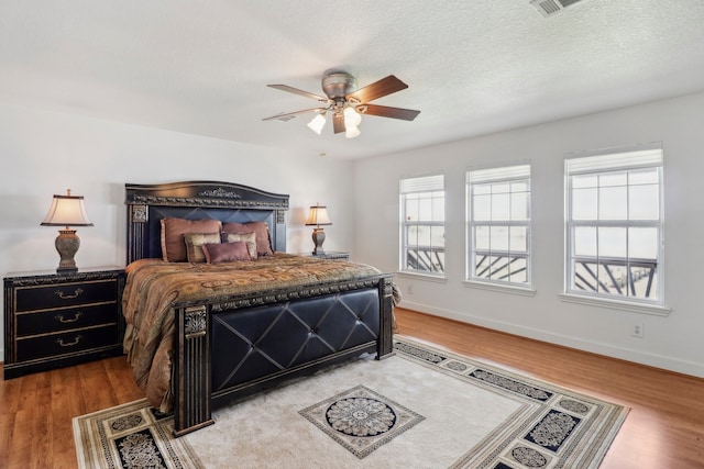 bedroom with ceiling fan, a textured ceiling, and light hardwood / wood-style flooring