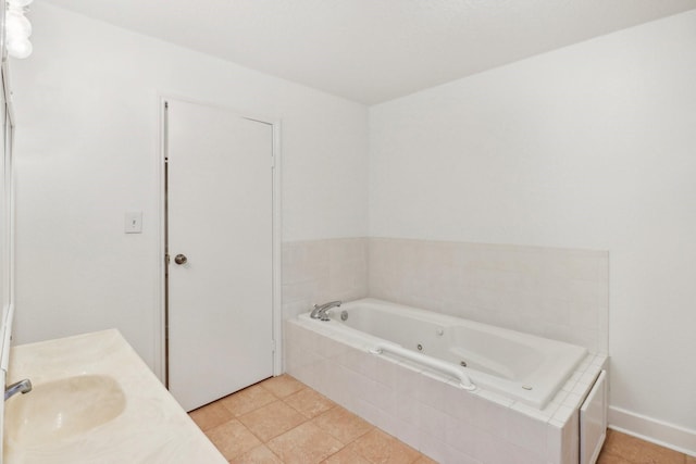 full bath featuring baseboards, a tub with jets, a sink, and tile patterned floors