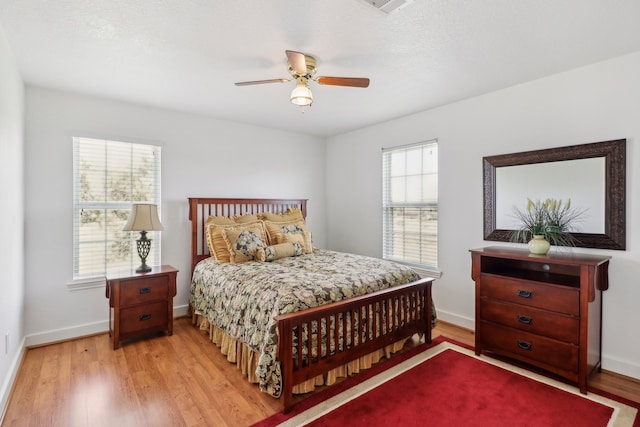 bedroom with multiple windows, ceiling fan, and light wood-type flooring