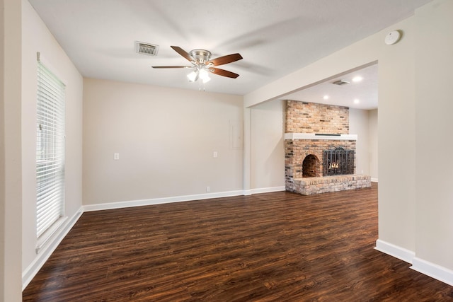 unfurnished living room featuring a brick fireplace, baseboards, visible vents, and wood finished floors