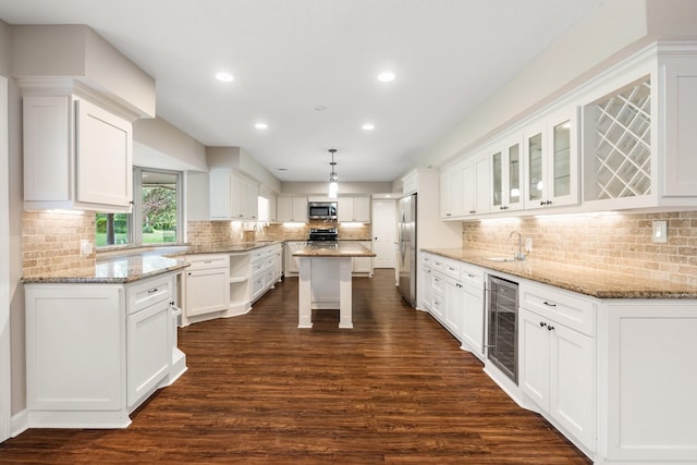 kitchen featuring dark wood-style floors, stainless steel appliances, white cabinets, a sink, and beverage cooler