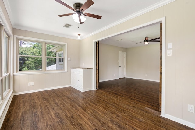 empty room with dark wood-type flooring, visible vents, and crown molding