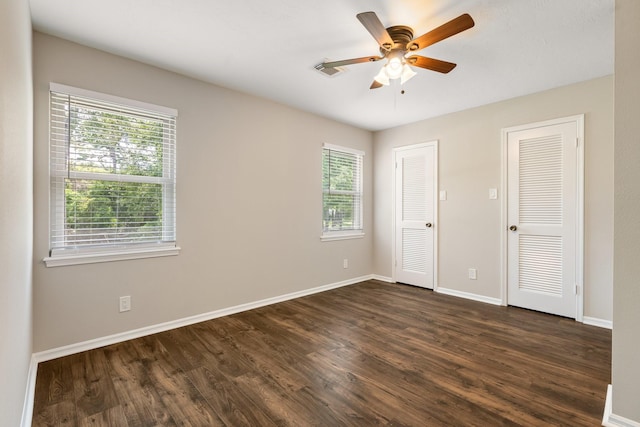 unfurnished room featuring dark wood-style floors, plenty of natural light, baseboards, and a ceiling fan