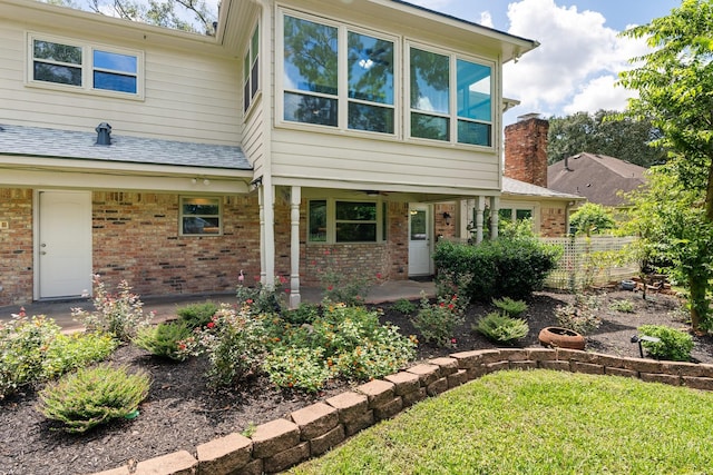 view of front of house featuring a shingled roof, fence, a patio, and brick siding