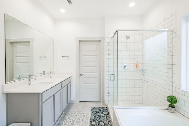 bathroom with shower with separate bathtub, double sink vanity, and tile patterned flooring