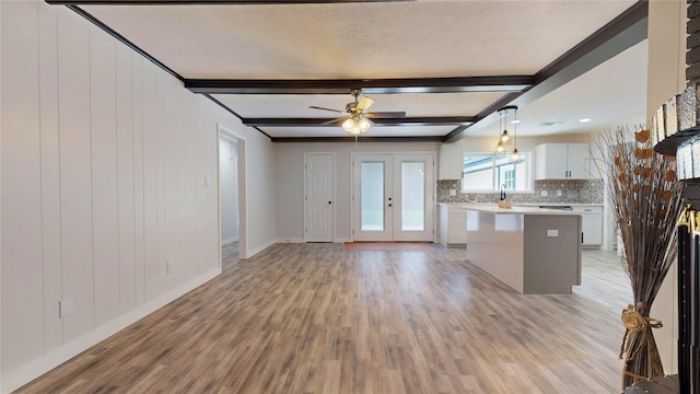 kitchen featuring white cabinets, beam ceiling, a center island, and pendant lighting