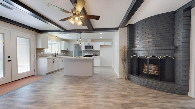 kitchen with pendant lighting, a center island, light hardwood / wood-style flooring, white cabinetry, and stainless steel appliances