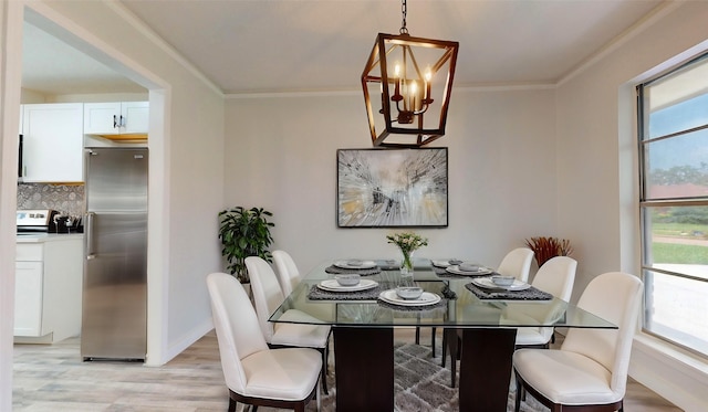 dining area with light wood-type flooring, ornamental molding, and a chandelier