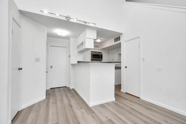 kitchen with light hardwood / wood-style flooring, kitchen peninsula, and rail lighting