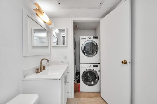 laundry area featuring light tile patterned flooring, stacked washer / dryer, and sink