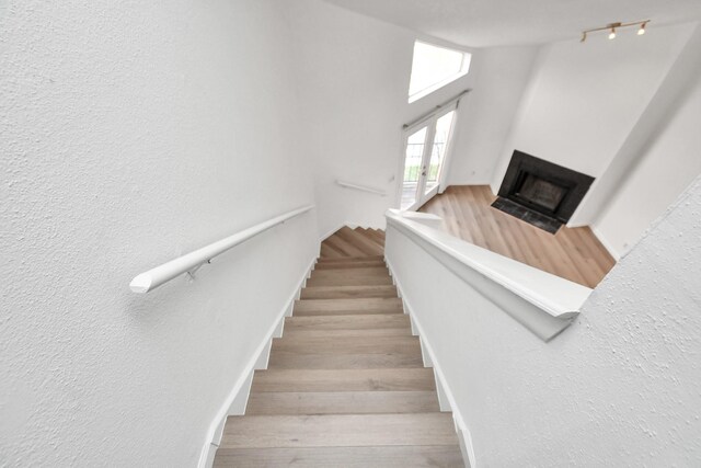 staircase with light wood-type flooring and track lighting