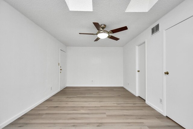 unfurnished bedroom with a skylight, light hardwood / wood-style flooring, and a textured ceiling