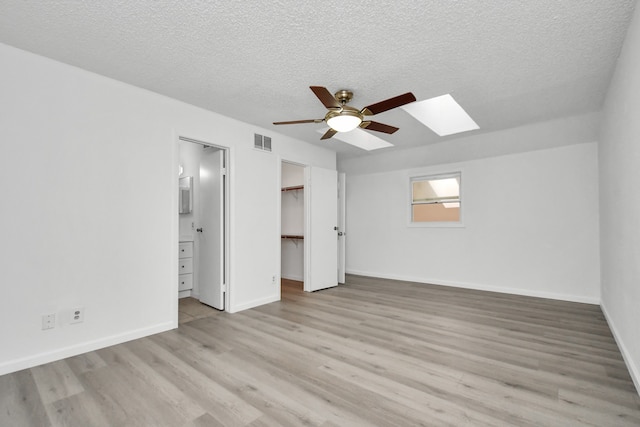 unfurnished bedroom with a skylight, light hardwood / wood-style floors, and ceiling fan