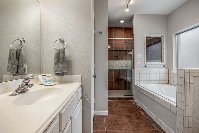 bathroom with shower with separate bathtub, vanity, a textured ceiling, and tile patterned flooring