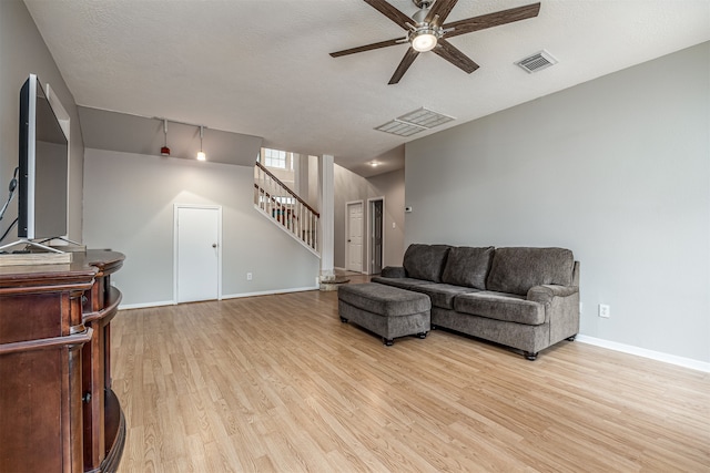 living room with light hardwood / wood-style flooring, a textured ceiling, and ceiling fan