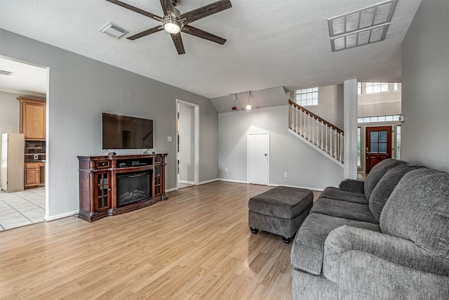 living room with ceiling fan, a textured ceiling, and light hardwood / wood-style flooring