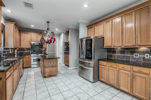 kitchen with stainless steel appliances, a kitchen island, pendant lighting, sink, and dark stone countertops