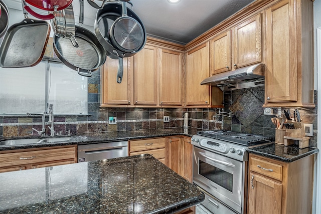 kitchen with backsplash, appliances with stainless steel finishes, a textured ceiling, sink, and dark stone countertops