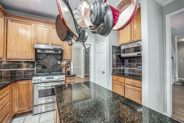 kitchen with dark stone counters, decorative backsplash, light tile patterned flooring, and stainless steel appliances