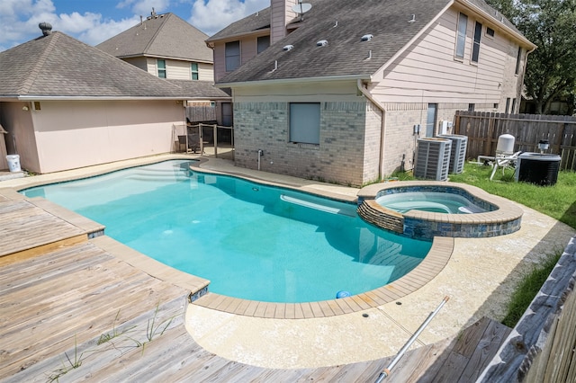 view of swimming pool with central air condition unit and an in ground hot tub