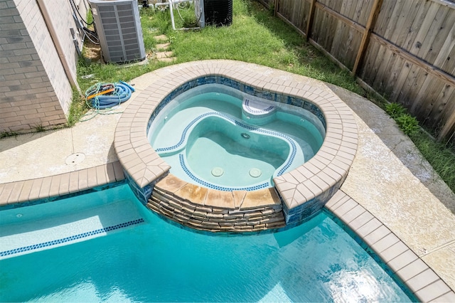 view of swimming pool featuring central AC unit and an in ground hot tub