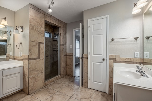 bathroom featuring tile walls, vanity, a textured ceiling, and a shower with door