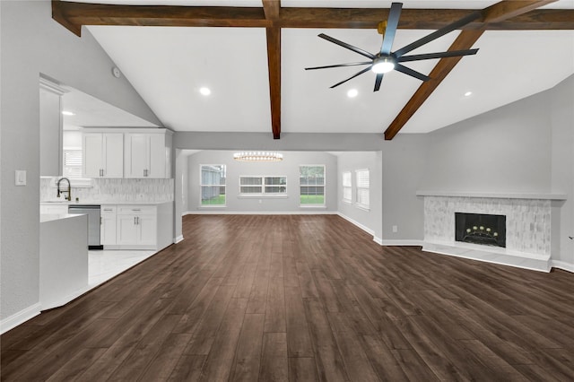 unfurnished living room featuring ceiling fan with notable chandelier, a fireplace, wood-type flooring, and vaulted ceiling with beams